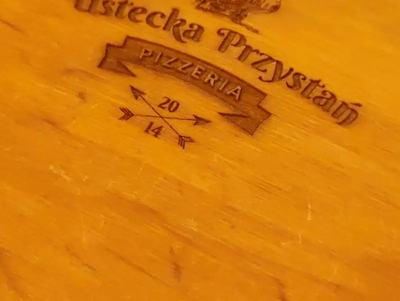 Logo Ustecka Przystań z żaglowcem wypalone na drewnianej desce